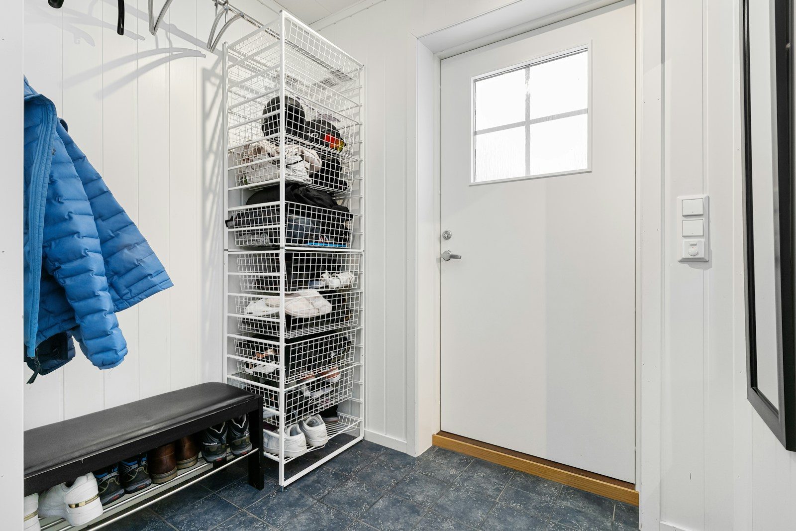 A walk in closet with a coat rack and shoes